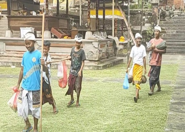 NGAMBENG : Anak-anak ngayah ngambeng menerima persembahan sarana upakara dari Krama untuk Pura Samuantiga, rahina Tilem Kedasa, Jumat (1/4). (ISTIMEWA)