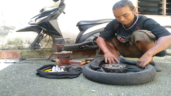 GARAP : Wayan Sutama saat menggarap salah satu sepeda motor pelanggannya. Krisna Pradipta/Bali Express