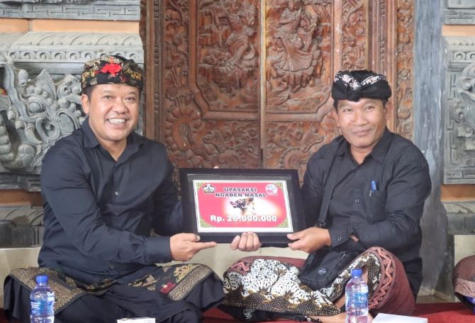 Bupati Bangli Sang Nyoman Sedana Arta (kiri) menyerahkan bantuan belanja banten upasaksi ngaben massal.