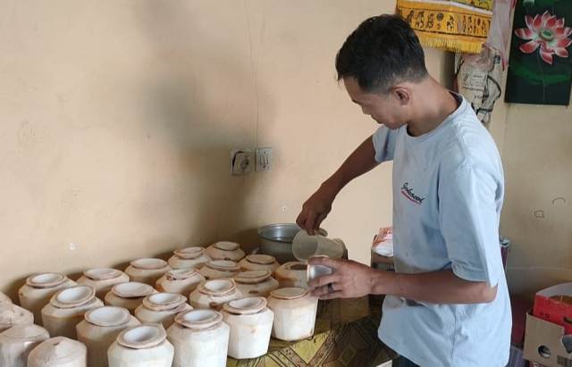 COCONUT JELLY DRINK: Kadek Agus Heri Susantho sedang memasukkan larutan kelapa jeli ke dalam buah kelapa. (DIAN SURYANTINI/BALI EXPRESS)