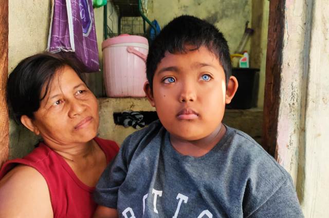 BERMATA BIRU: Ketut Adi Putra dengan mata birunya yang indah didampingi ibunya. (DIAN SURYANTINI/BALI EXPRESS)