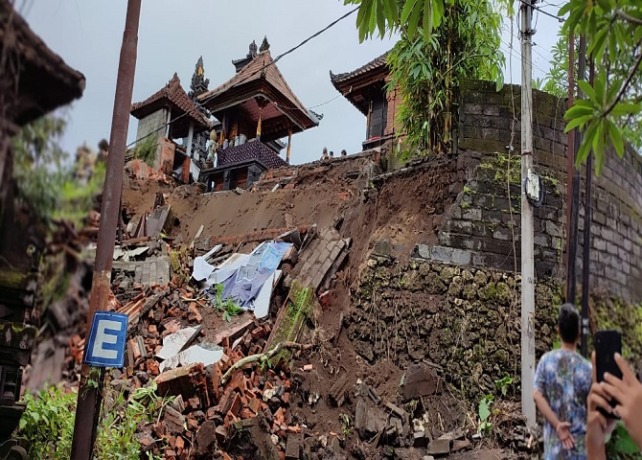 AMBRUK: Tembok serta senderan Pura Dalem Jagad Dalem Sidakarya ambruk akibat longsor dan materialnya menimbun badan jalan. (ISTIMEWA)