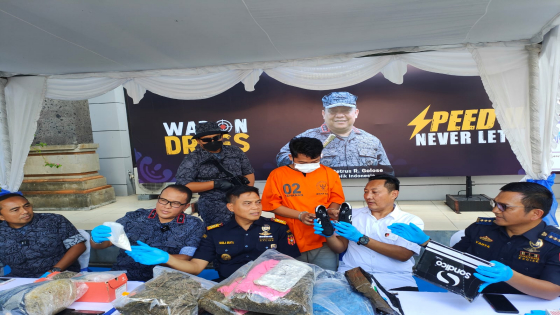 TERCIDUK : AJ menunjukkan sepatu yang dipakai sebagai kamuflase paket untuk kiriman kokain, saat kasusnya dibebberkan di BNNP Bali. Agung Bayu/Bali Express
