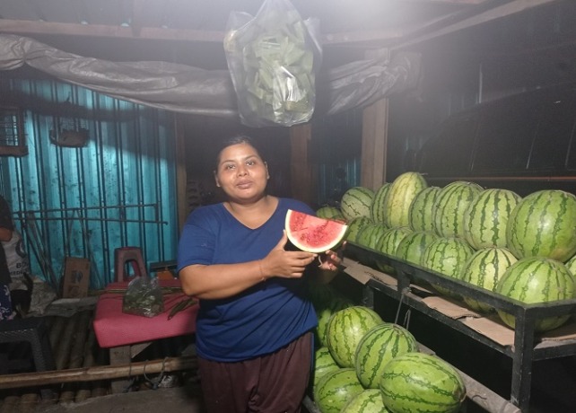 NAIK HARGA Salah satu penjual semangka I Wayan Eti saat menunjukkan semangka yang ia jual, Selasa (14/2). (ANANDA MUSTIKA/BALI EXPRESS)