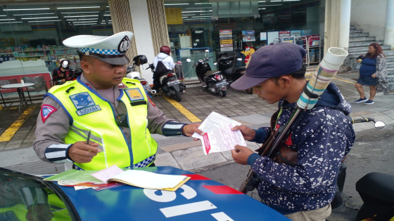 MELANGGAR: Personel Polda Bali memberikan teguran maupun tindakan tilang dengan sistem elektronik kepada pengendara yang secara kasat mata melanggar lalu lintas saat Ops Keselamatan Agung. Ist