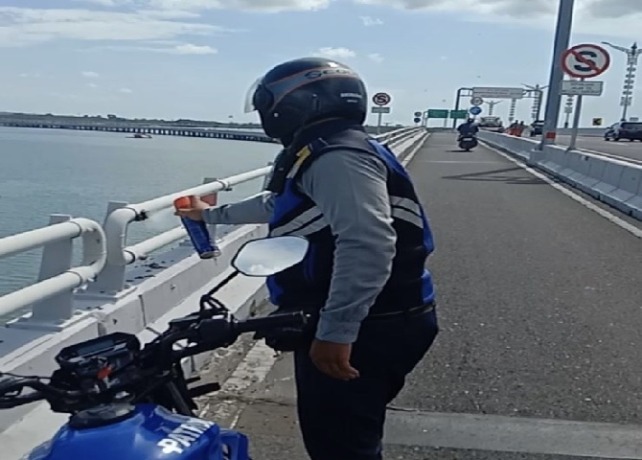 PENANGANAN: Seorang petugas mengusir gerombolan tawon di salah satu railing Jalan Tol Bali Mandara, Sabtu (18/3). (ISTIMEWA)