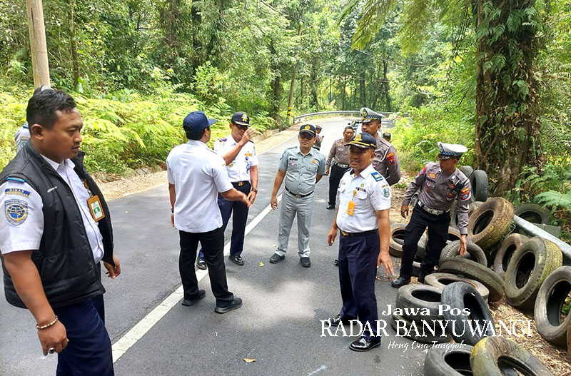 PENGAMAN: Petugas gabungan dari Satlantas dan Dishub Banyuwangi memasang ban pelindung di tikungan Sengkan Mayit, jalan menuju Ijen, Minggu (5/11).