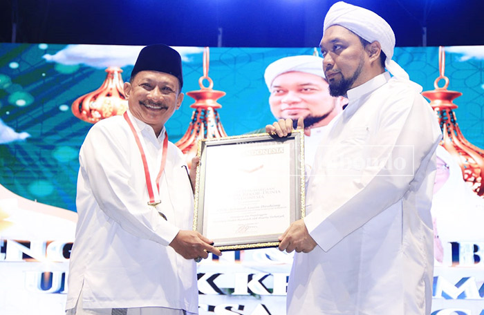 MEMBANGGAKAN: Bupati Situbondo, Drs. Karna Suswandi, Pengasuh Ponpes Salafiyah Syafi&rsquo;iya Sukorejo, KHR. Achmad Azaim Ibrahimy memegang piagam Rekor Muri Dunia, di alun-alun Situbondo.