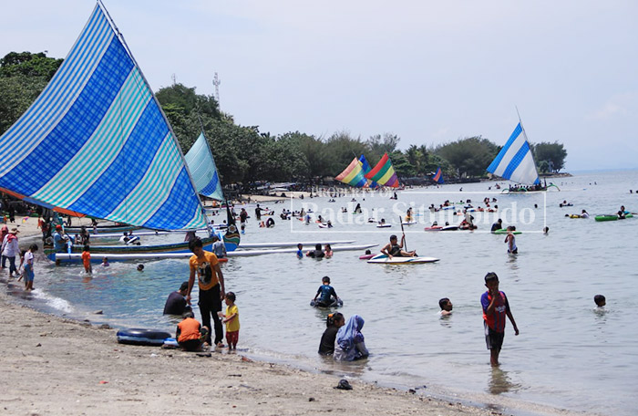 BERLIBUR: Suasana wisata Pantai Pasir Putih ramai dikunjungi masyarakat, di wilayah Desa Pasir Putih, Kecamatan Bungatan.