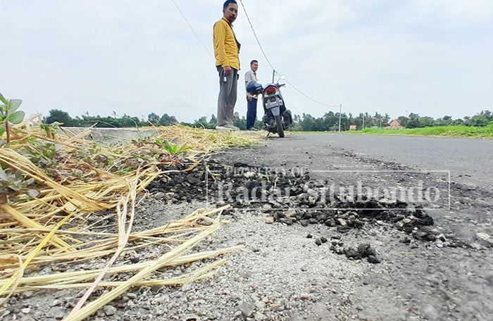 MENGELUPAS: Salah satu warga melihat kualitas penambalan keretakan aspal hotmix di Jalan Dusun Komirian, Desa Seletreng, Kecamatan Kapongan.