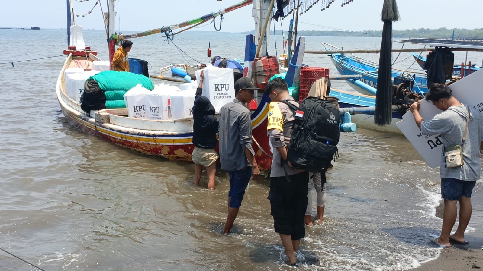 DISTRIBUSI : Petugas penyelenggara didampingi Polisi Polres Situbondo mengangkut logistik ke atas perahu, di Dusun Merak, Desa Sumberanyar, Kecamatan Banyuputih, Kamis (15/2)