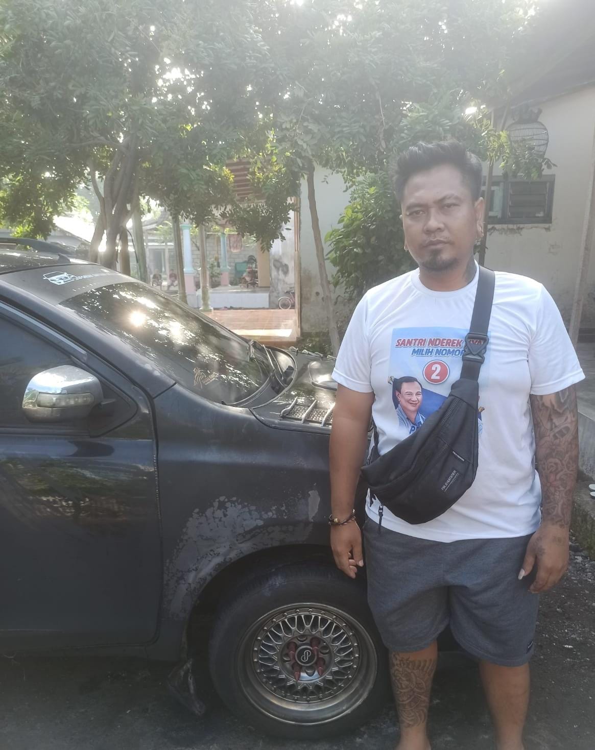 BB: Putu Budi Darmayasa di samping mobil miliknya yang dibakar OTK