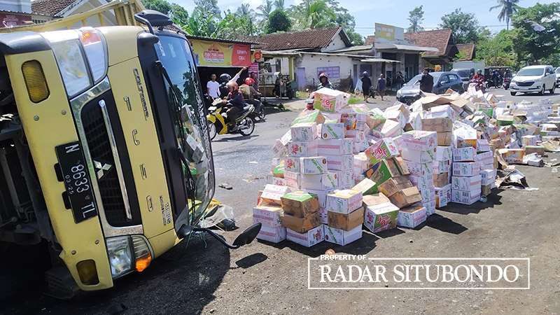 BERSERAKAN: Ribuan kardus minuman berserakan di jalan akibat truk yang membawa terguling di jalan raya Dusun Wadung Dollah, Desa Setail, Genteng, Banyuwangi, Selasa (5/3).