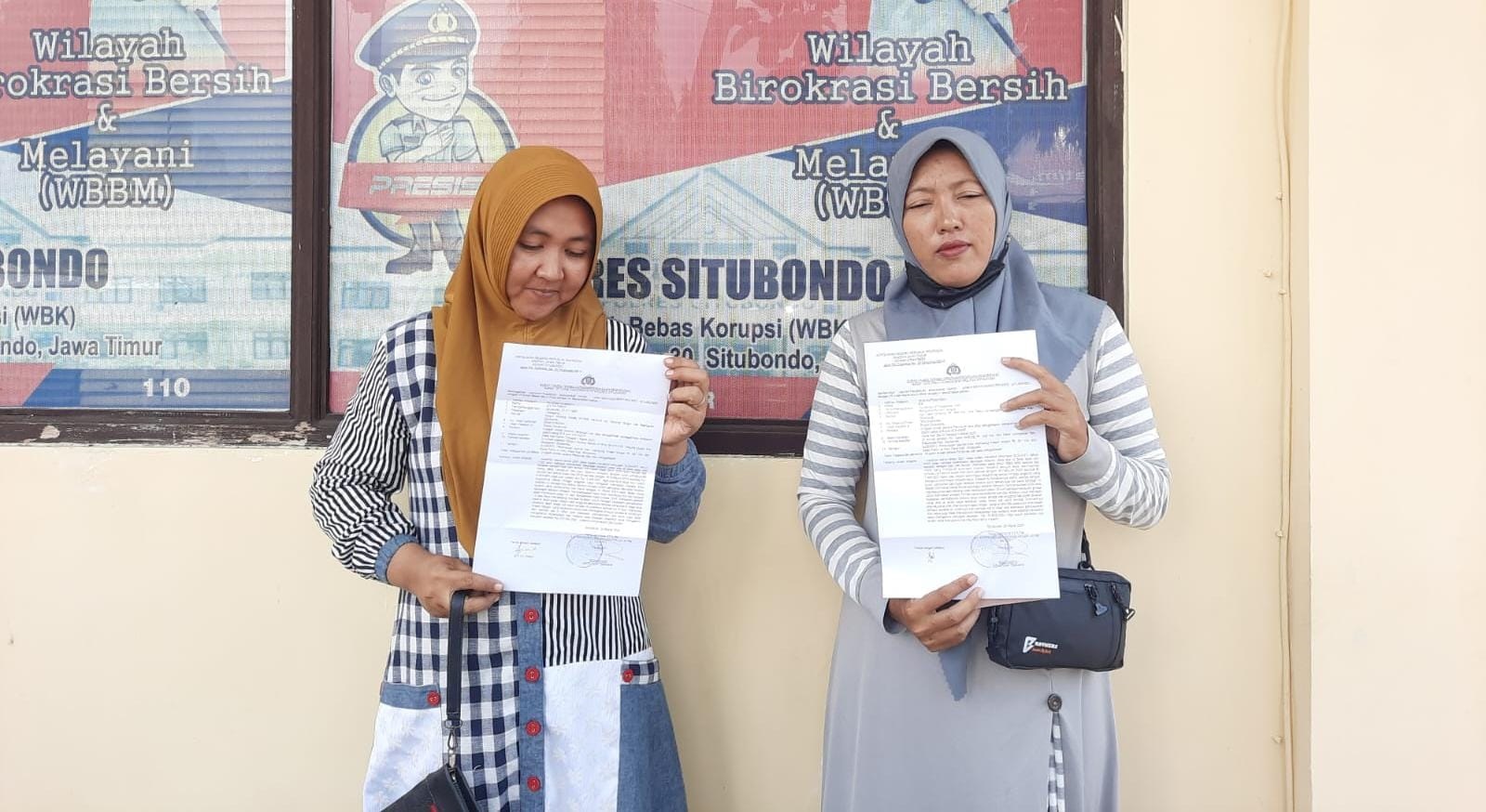 Dua ibu rumah tangga asal Desa Desa Tanjung Glugur, Kecamatan Mangaran, dan warga Desa Landangan, Kecamatan Kapongan, menunjukkan bukti laporan di halaman Polres Situbondo, Selasa (26/3).