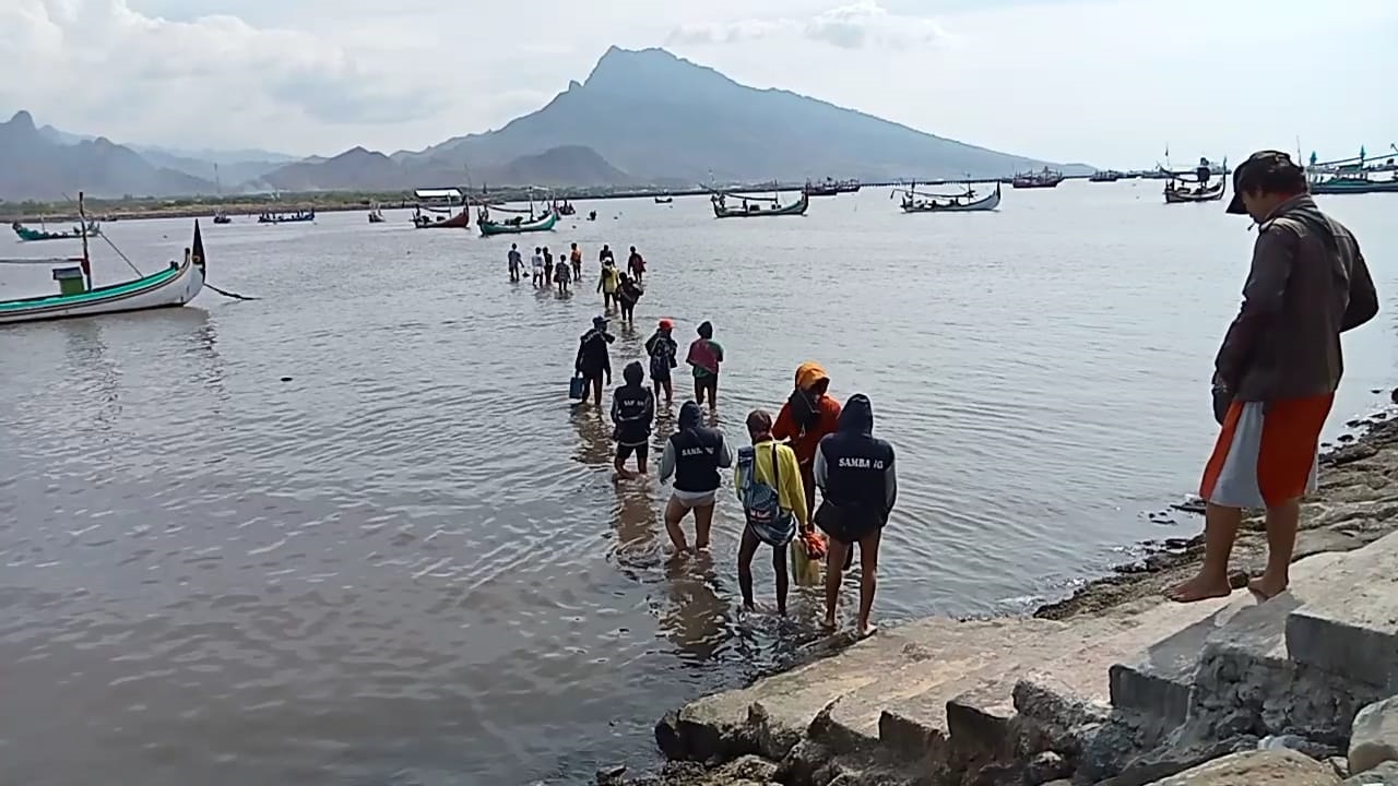 BERJEJER: Para nelayan jalan kaki menuju kapal yang ada di tengah laut, di Pesisir Panarukan, Desa Kilensari, Kecamatan Panarukan, Rabu (27/3).