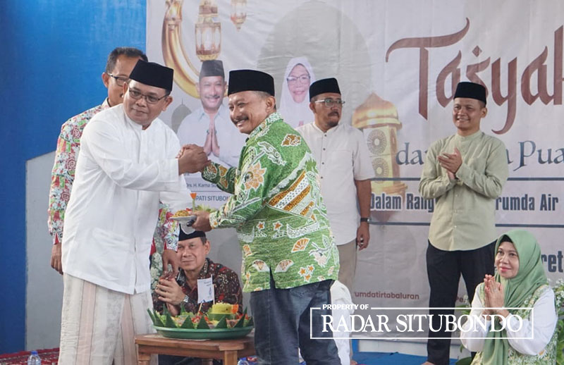 Direktur PDAM Tirta Baluran, Asya&rsquo;ri menerima potongan tumpeng dari Bupati Situbondo, Drs. Karna Suswandi, di kantor PDAM Tirta Baluran, Lingkungan Karangasem, Kelurahan Patokan