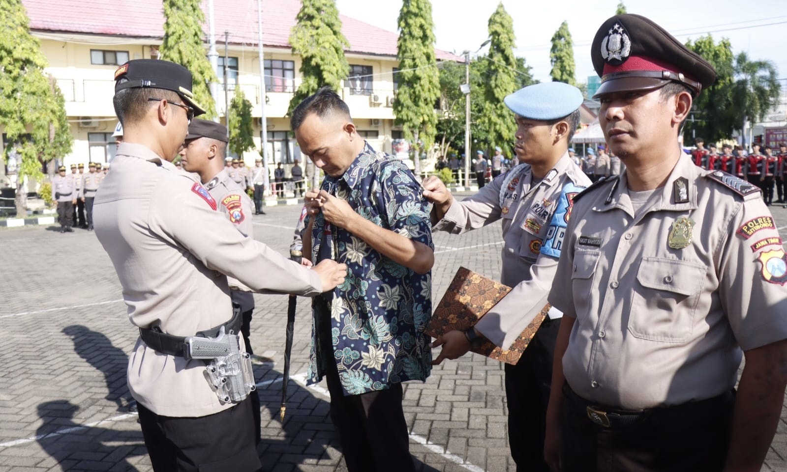 LANGKAH TEGAS: Kapolres Situbondo AKBP Dwi Sumrahadi Rahkmanto melepas baju dinas salah satu anggota yang dipecat dalam apel PTDH, di halaman Polres Situbondo, Rabu (3/4).