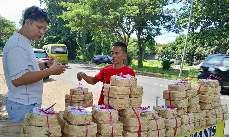 LARIS MANIS: Nawardi (kanan) menawarkan tape pada pembeli di pinggir jalan raya Desa Panji Kidul, Panji, Situbondo, Jumat (12/4).