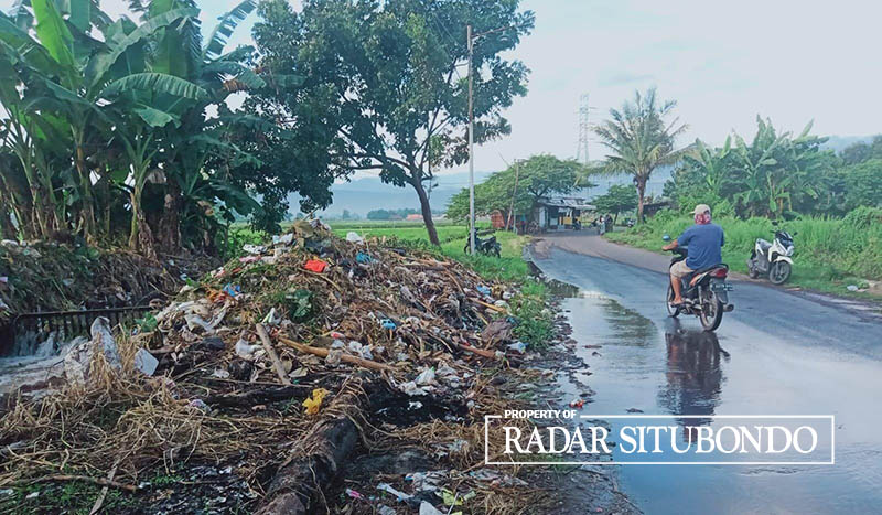 DIKELUHKAN:  Pengendara motor melintas di dekat tumpukan sampah di pinggir Jalan Dusun Janti, Desa Ketah, Kecamatan Suboh, Situbondo, Jumat (26/4).