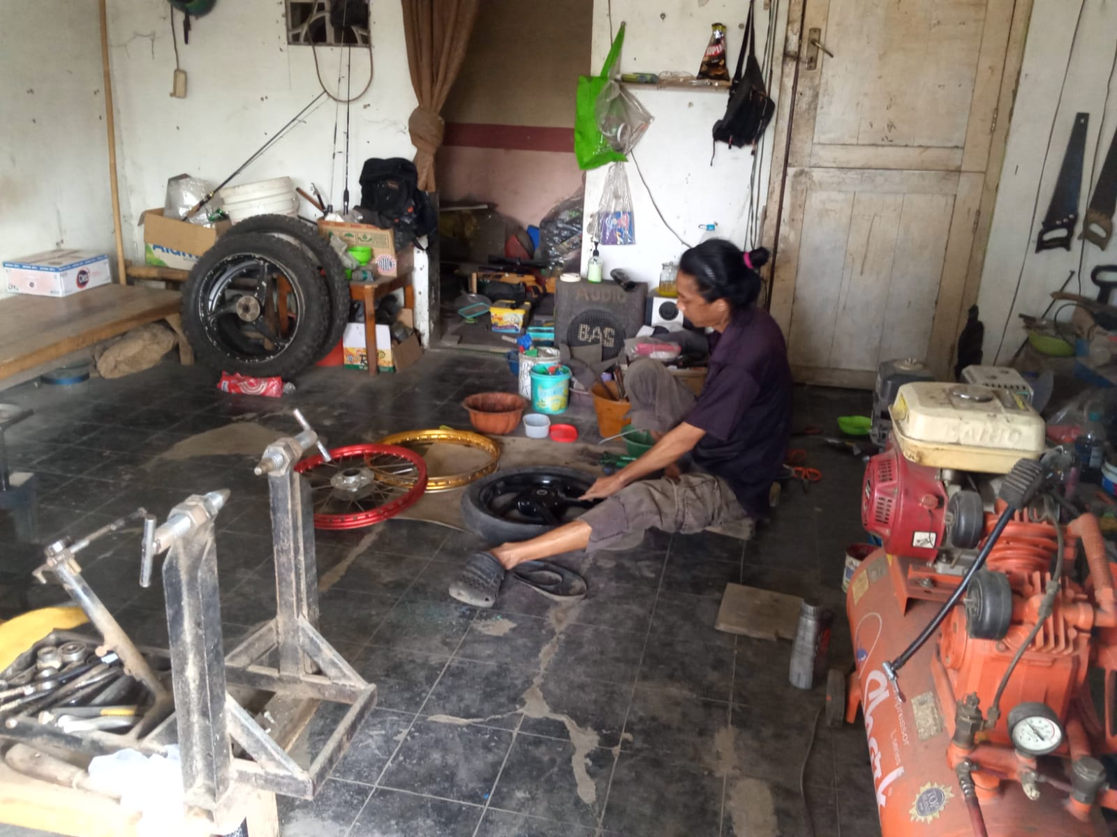 KORBAN: Seorang pengendara motor memperbaiki peleg motornya yang bengkok setelah melewati jalan rusak di jalur pantura, Jumat (10/5).