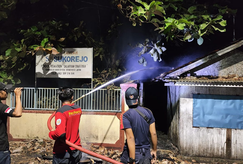 Petugas BPBD Situbondo melakukan pembasahan di sekitar rumah Ahmad agar api tidak merembet ke tempat lain.