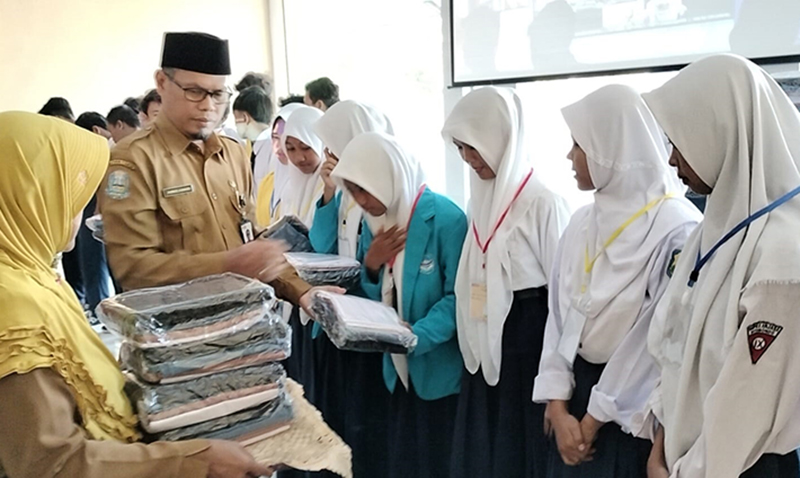 BAGI SERAGAM: Kepala SMAN 1 Kapongan (SMANKA) membagikan baju gratis kepada sejumlah siswa, di hari masuk pertama, Senin (15/7).
