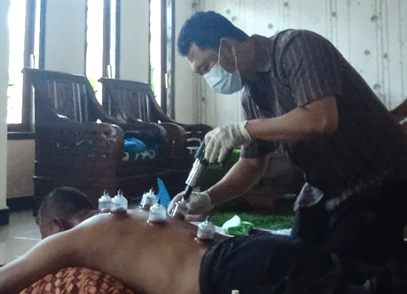 TERAMPIL: Jasa bekam merangkap tukang pijat di Kelurahan Dawuhan, Kelurahan Patokan, Situbondo, diminati warga, Selasa (16/7).