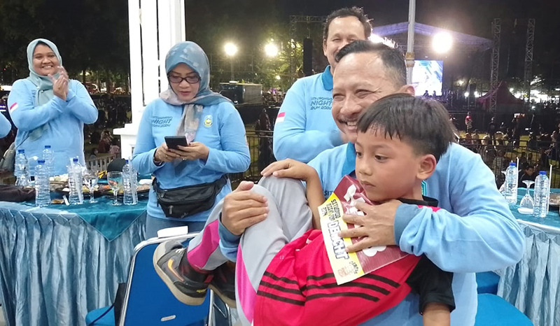 PERDANA: Bupati Situbondo Karna Suswandi membopong Nevi, peserta termuka Situbondo Night Run di alun-alun Situbondo.