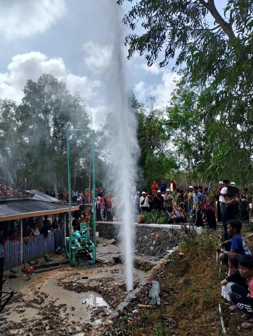 Warga menyaksikan semburan air di area pengeboran sumur milik Rokip, Desa Pandan, Kecamatan Omben, Sampang, Jumat (2/8).