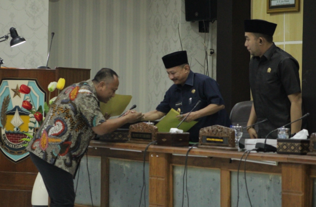 PERDANA : Ketua Fraksi Partai Golkar, Rachmad menyerahkan berkas pemandangan umum fraksi kepada pimpinan DPRD, Mahbub Junaidi di ruang rapat paripurna DPRD Situbondo, Jumat (20/9)