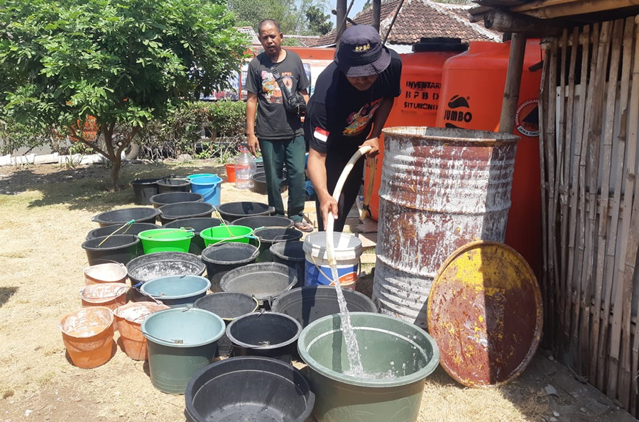 BERGANTIAN: Petugas BPBD menyalurkan air bersih untuk warga di Dusun Karangnangka, Desa Selowogo, Bungatan, Situbondo, Sabtu (12/10) lalu.