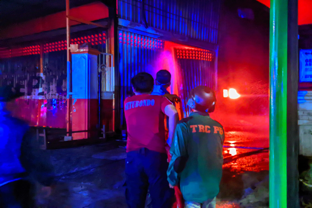 Petugas damkar hanya menggunakan kaos saat memadamkan kebakaran bengkel mobil di Kelurahan Mimbaan, Kecamatan Panji, Situbondo, Kamis malam (16/10).