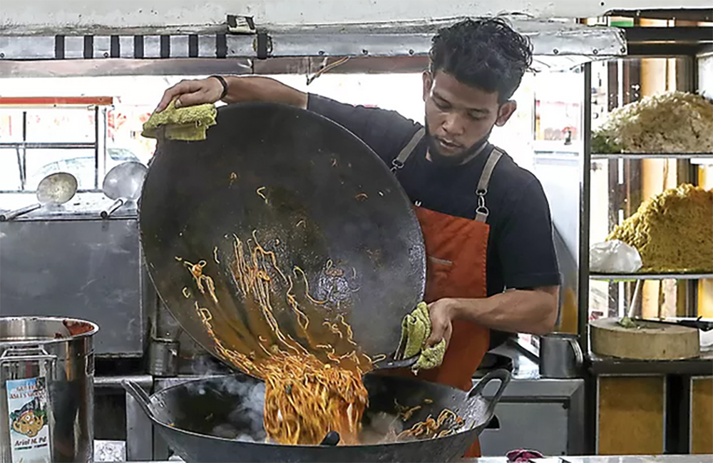 BUKAN MILIK WANITA: Munzir memasak mi Aceh daging di kedai Mie Razali, Banda Aceh. Laki-laki yang bisa memasak itu keren. (Hendra Eka/Jawa Pos)