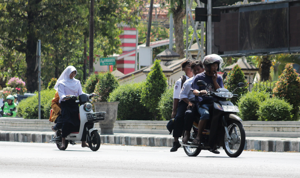 GUNAKAN SERAGAM LENGKAP: Seorang siswi mengemudikan kendaraan roda setelah pulang sekolah di jalan Wijaya Kusuma, Patokan, Situbondo, Senin (21/10).
