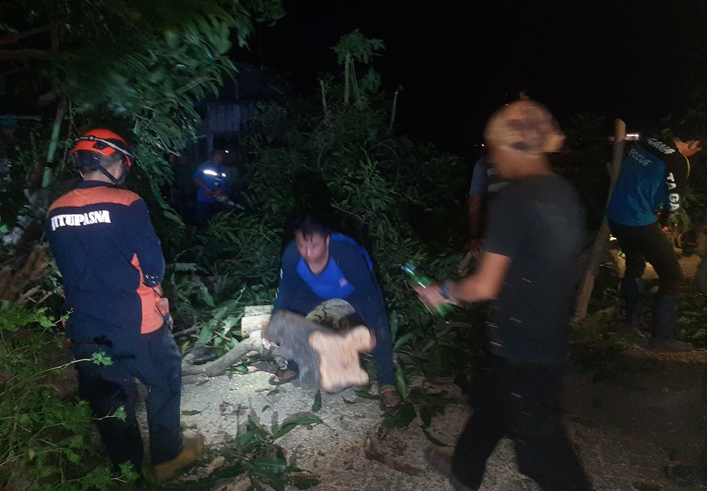 EVAKUASI: Petugas BPBD bersama Tagana memotong batang kayu yang menimpa rumah keluarga Ajib di Kelurahan Dawuhan, Kecamatan Kota, Sabtu malam (26/10).