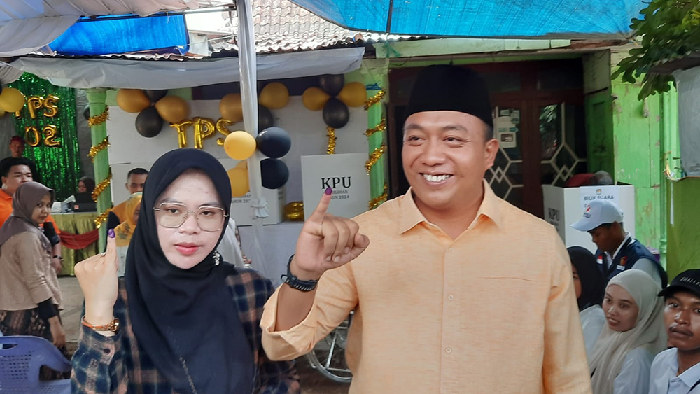 Yusuf Wahyu Rio Prayogo bersama sang istri Usna Laili menunjukkan tanda bukti pencoblosan, di luar TPS 02 Desa Trebungan, Kecamatan Mangaran, Rabu (27/11).