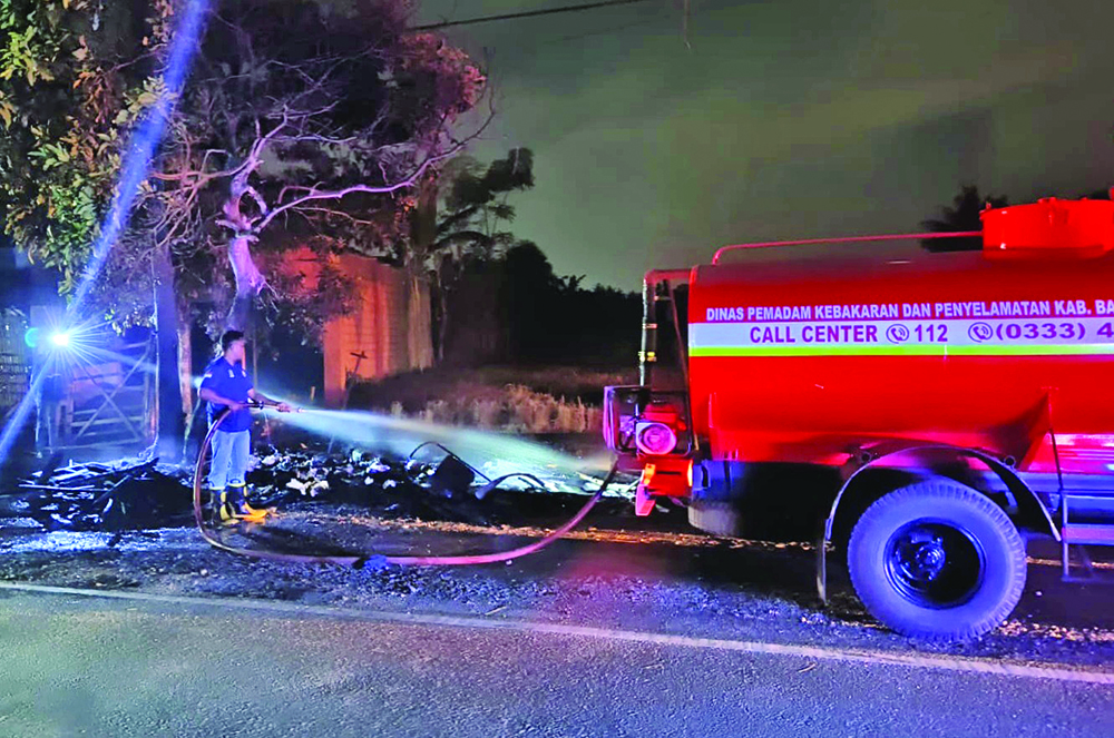 PEMADAMAN: Anggota Damkar Sektor Genteng memadamkan api yang membakar kedai buah di pinggir jalan Dusun Krajan Wetan, Temuguruh, Sempu, Kamis (9/1) malam