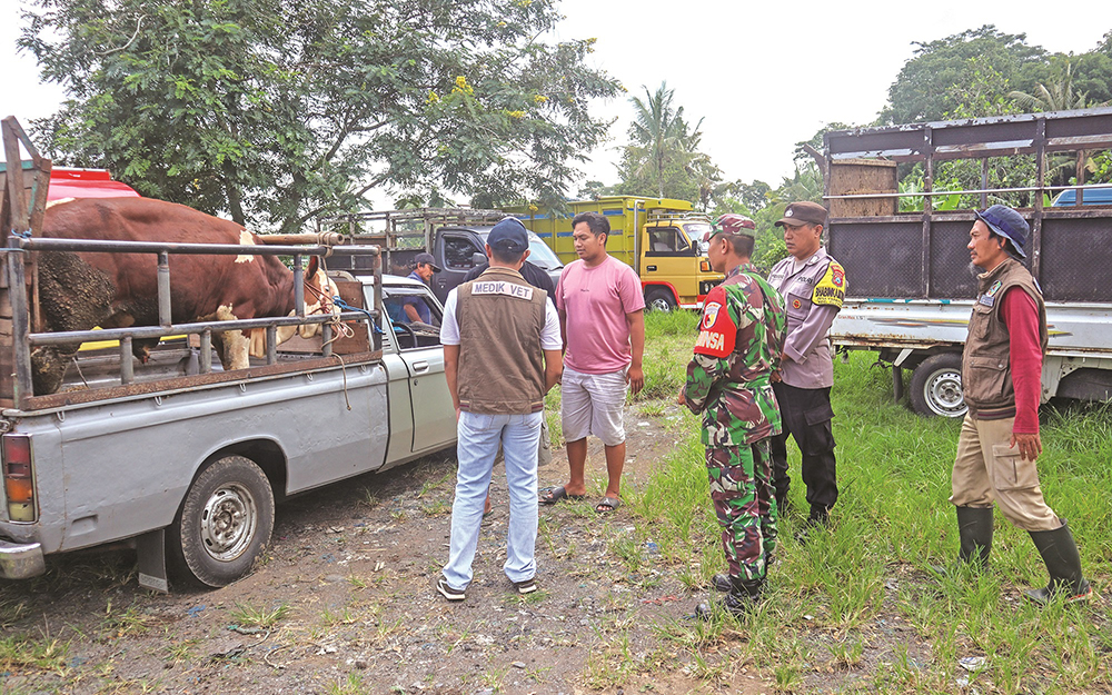 DILARANG MASUK: Petugas gabungan dari kepolisian, TNI, dan Dispertapan memberi pengertian kepada pedagang sapi dari luar Banyuwangi yang masuk ke Pasar Hewan Karangharjo, Glenmore, Jumat (10/1).