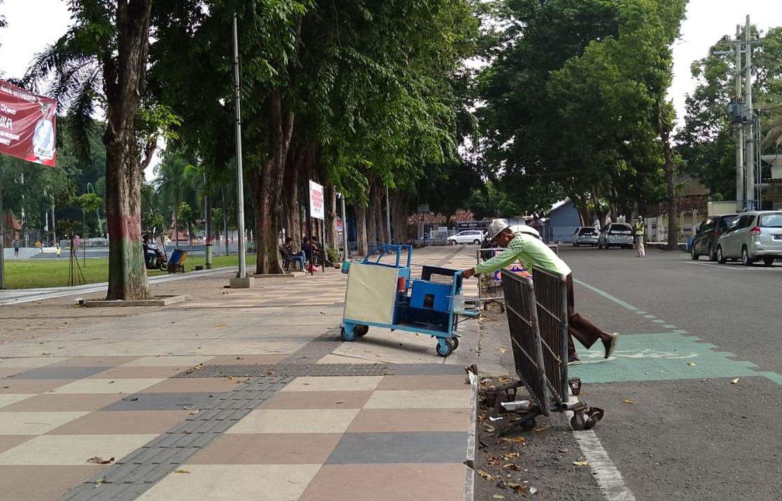 DIDORONG: Salah seorang pedagang di membawa gerobaknya ke dalam Alun-Alun Situbondo, Kamis (27/2).