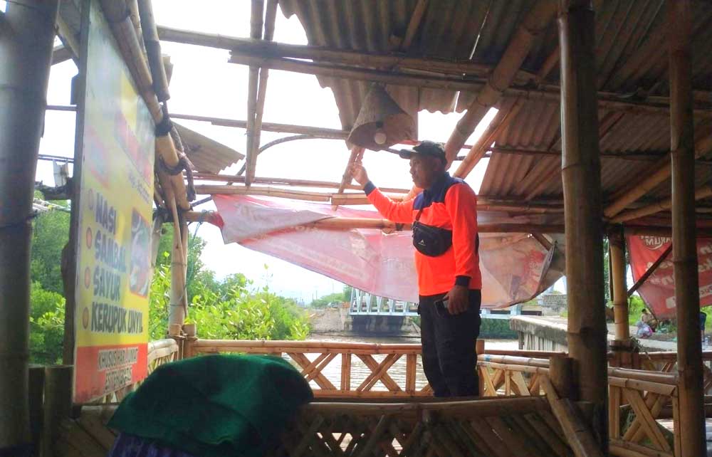 Petugas BPBD Situbondo melihat atap warung yang hilang diterjang angin.