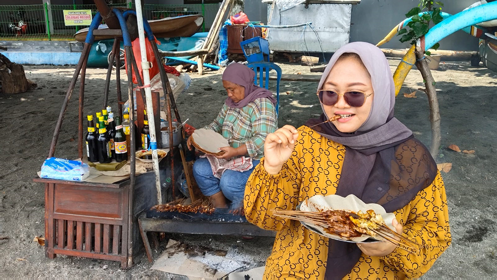 Warga menikmati sate lalat di Pasir Putih Situbondo. Sementara Rosa Aminatun mempersiapkan pesanan pelanggan, Kamis (3/4).