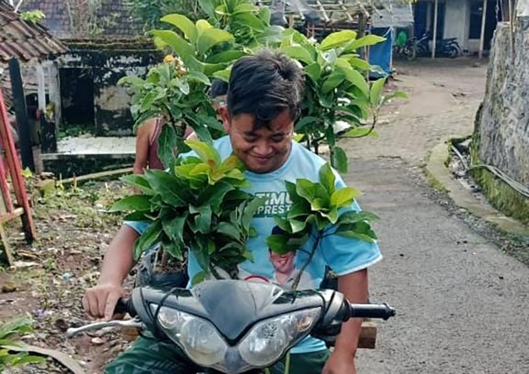 Warga membawa bibit alpukat siap untuk ditanam di lahan milik Perhutani yang gundul di Sumbermalang, Situbondo. (Humaidi/Radar Situbondo)