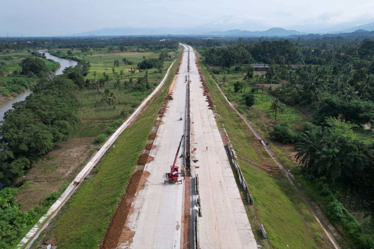 Operator alat berat melakukan pemasangan guradrail dari bahan beton cor di ruas proyek jalan tol Padang, Sumatera Barat.