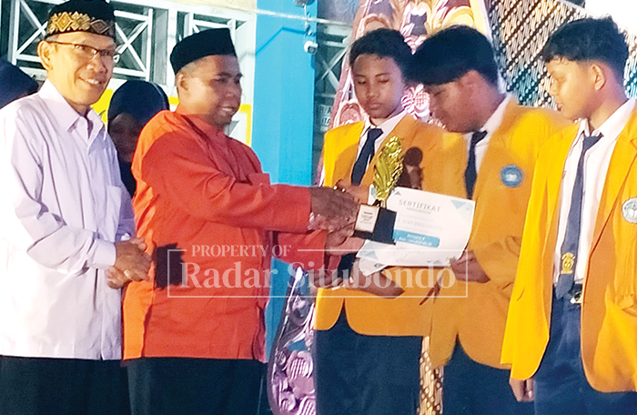Plt. Kepala Dinas Pendidikan dan Kebudayaan Kabupaten Situbondo, Dr. Fathor Rakhman didamping Kepala SMPN 5 Situbondo, Agus Triono, M.Pd menyerahkan tropy dan piagam penghargaan kepada siswa