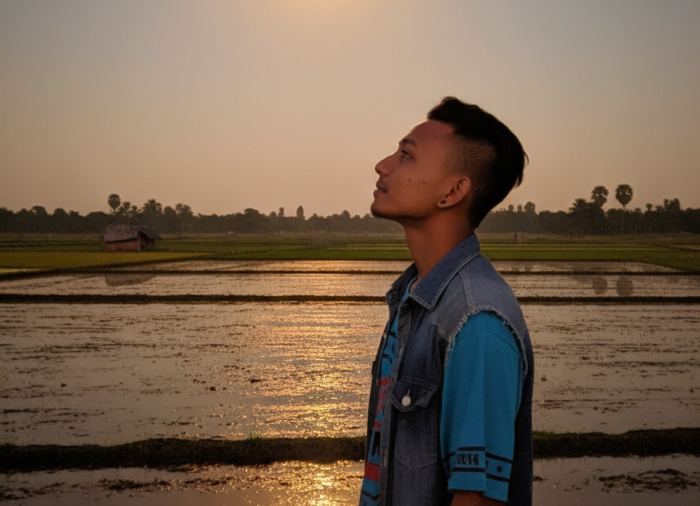 Seorang pria sedang berada di area persawahaan.