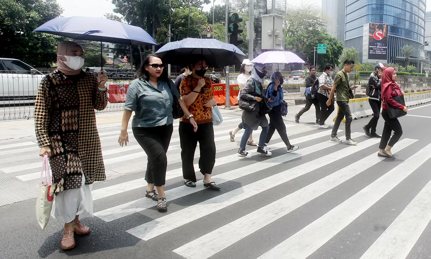 Warga melintas di tengah cuaca panas.