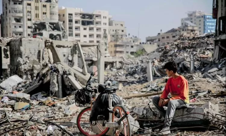 Seorang pemuda Palestina duduk di samping sepedanya di tengah puing-puing bangunan yang hancur di Kota Gaza di jalur Gaza utara setelah berminggu-minggu pemboman Israel.