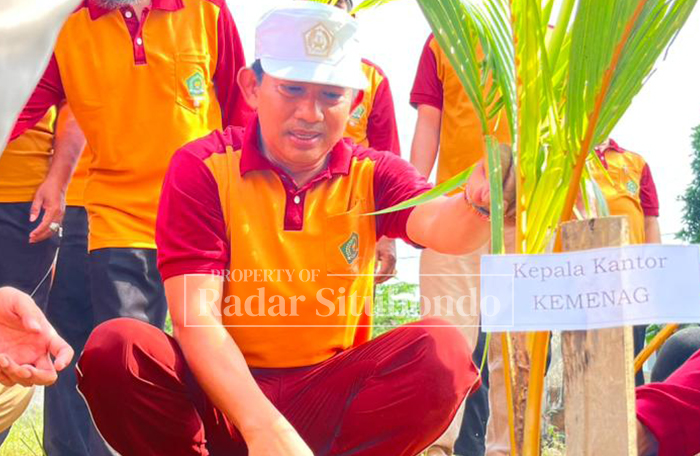 PEDULI LINGKUNGAN: Kepala Kantor Kemenag Situbondo, Muhammad Mudhofar menanam pohon dalam acara ekoteologi, Selasa (30/12).