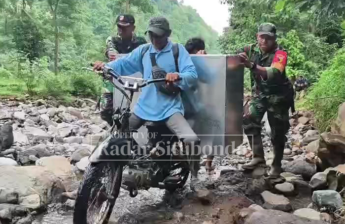 MEDAN EKSTREM: Kendaraan pengantar MBG didorong anggota TNI saat melintas di pinggir sungai Desa Patemon, Kecamatan Jatibanteng, Rabu (28/1).
