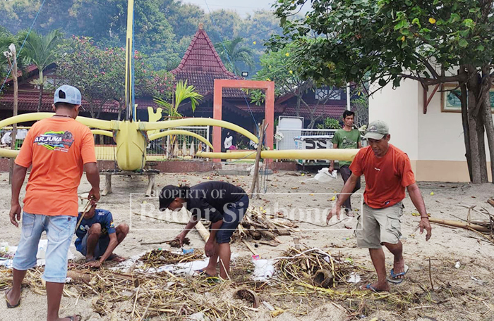 GOTONG ROYONG: Pelaku wisata dan pelaku Usaha Mikro, Kecil, dan Menengah (UMKM) di Wisata Bahari Pasir Putih, Kecamatan Bungatan, Situbondo, membersihkan sampah dan ranting kayu.
